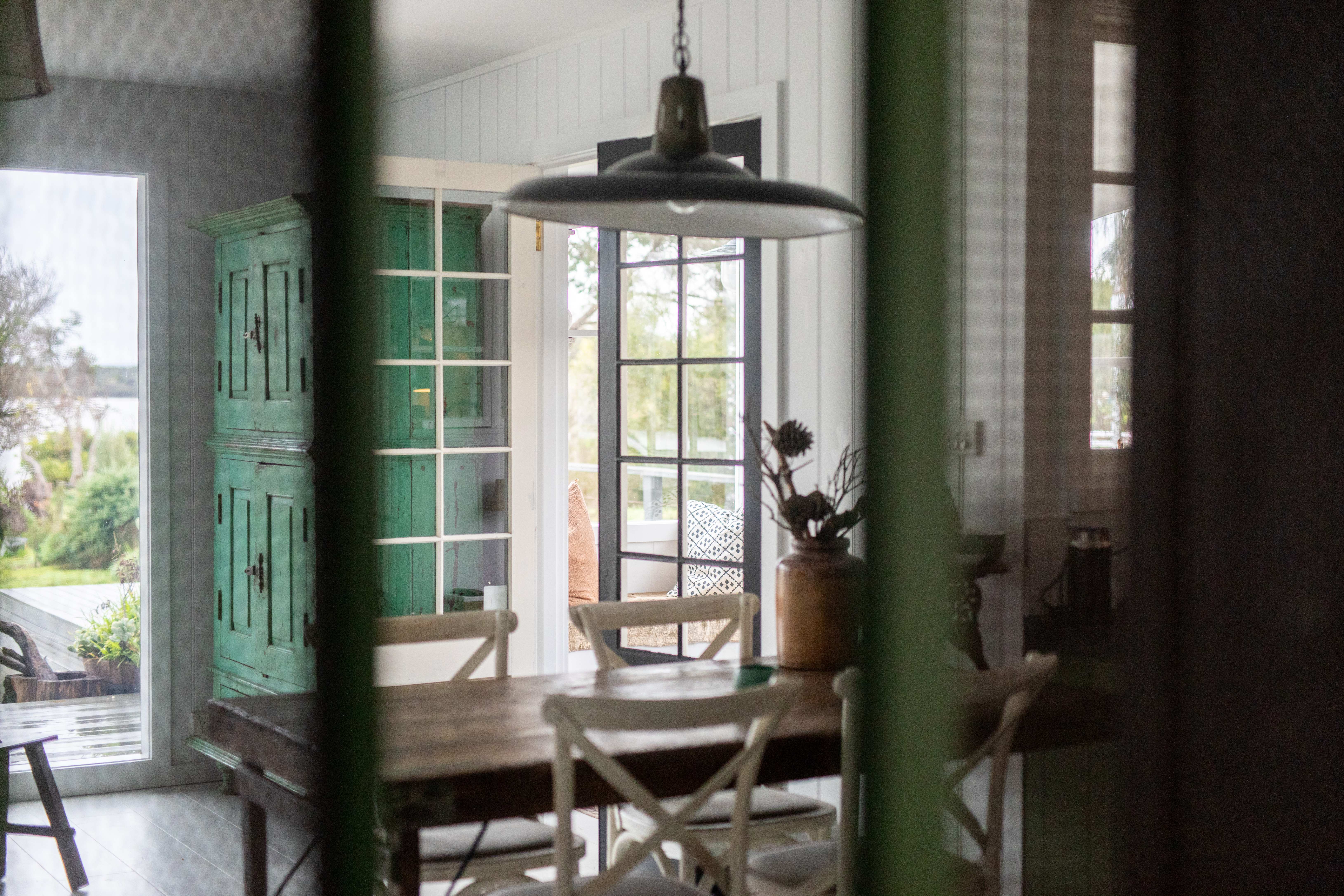 A styled boutique interior with a vintage green cabinet and French doors opening to greenery