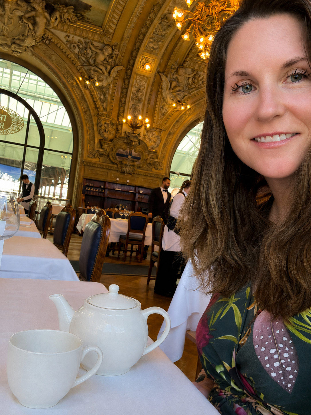 Kirsty Dunphey with a white teapot and cup in the ornate, golden dining room of Le Train Bleu in Paris